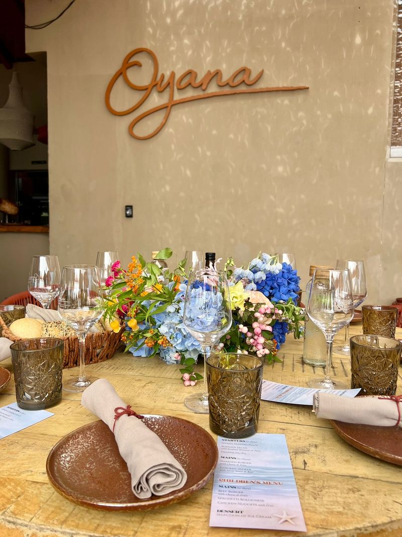 A celebration table set with flowers, glassware and menus beneath the Oyana sign