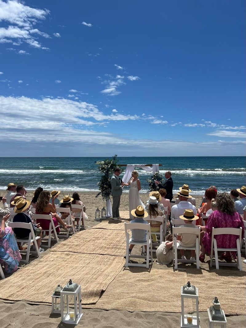 A wedding ceremony on the beach with guests seated facing the sea