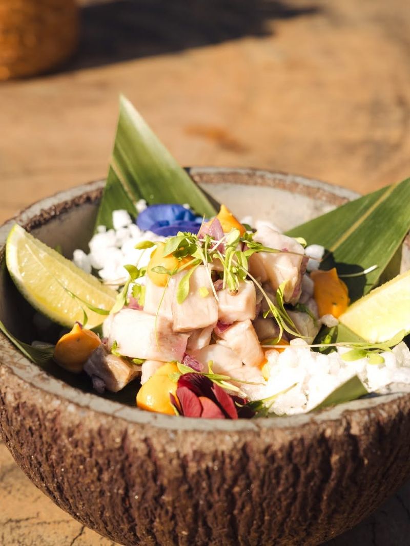 A ceviche-style bowl of fish, lime and edible flowers in a coconut shell