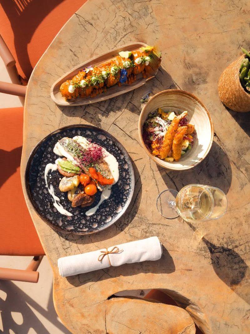 Overhead view of several sharing plates and white wine on a round wooden table