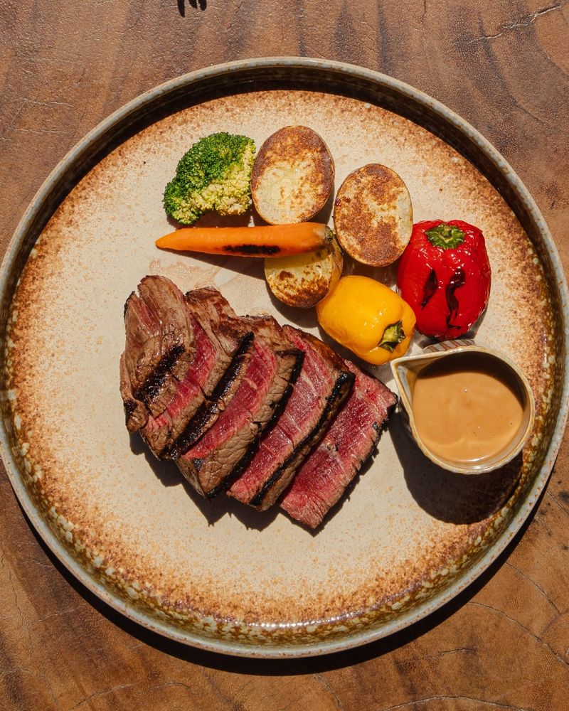 Sliced grilled beef with peppercorn sauce, baby potatoes and grilled vegetables