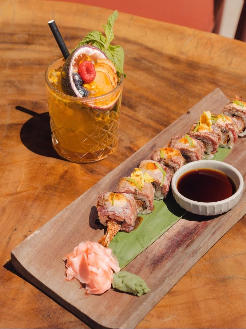 Sushi rolls with soy and pickled ginger beside a cocktail