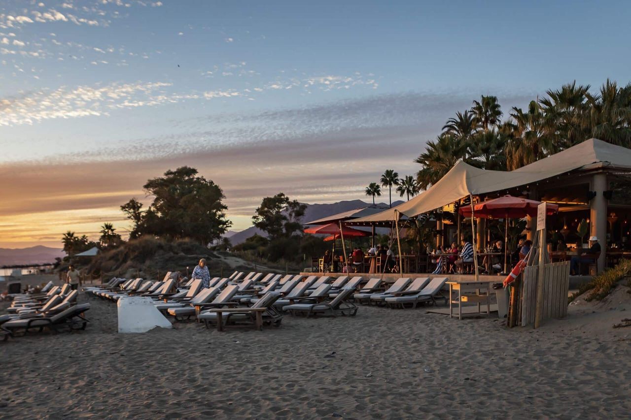 Oyana’s beach and canopies at sunset with the mountains behind